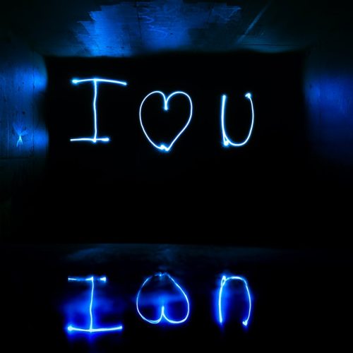 Blue neon light painting 'I love you' in a reflective dark tunnel.